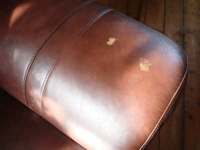 Scuffed brown leather sofa arm