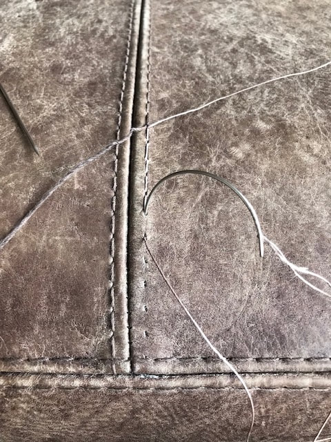 Broken stitching on grey leather sofa
