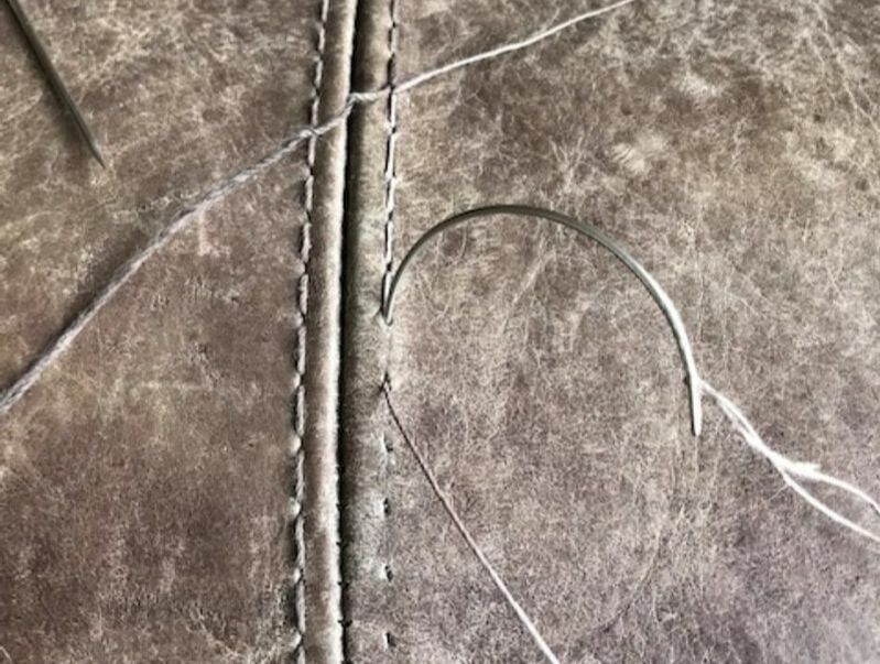Broken stitching on grey leather sofa