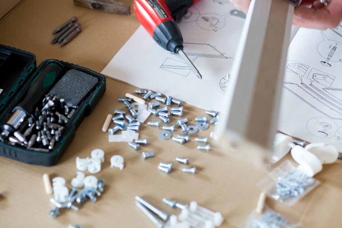 Man using a drill and screws to assemble a piece of flat-pack furniture