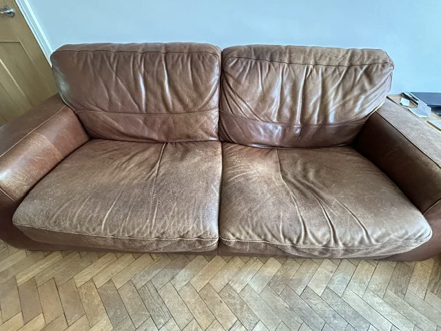 Sagging brown-leather sofa seat before restoration